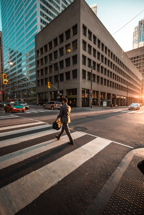 A man walking across a crosswalk in a city